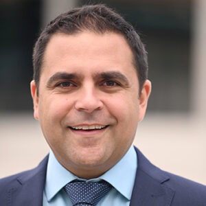 Mann in Anzug und Krawatte lächelt in die Kamera.