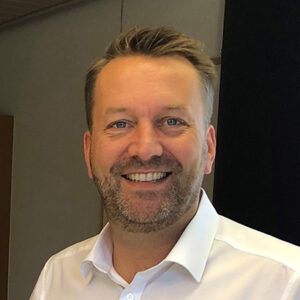 Ein lächelnder Mann in einem weißen Hemd.