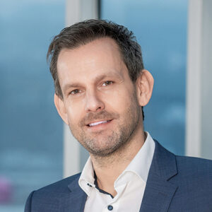 Ein Mann in Anzug vor einem Fenster.