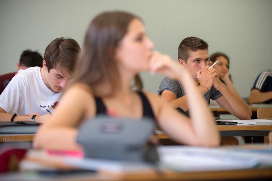 Schülerinnen und Schüler sitzen in einem Klassenraum und folgen dem Unterricht.