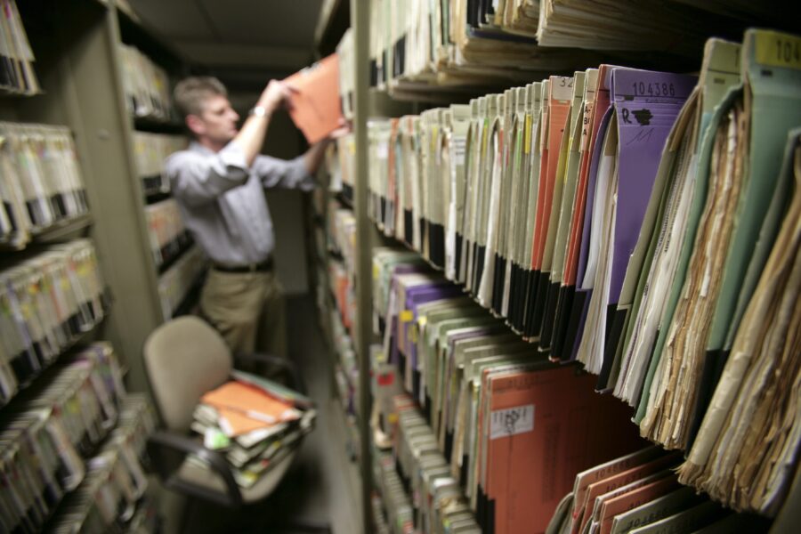 Mann durchwühlt Akten in einem Archiv