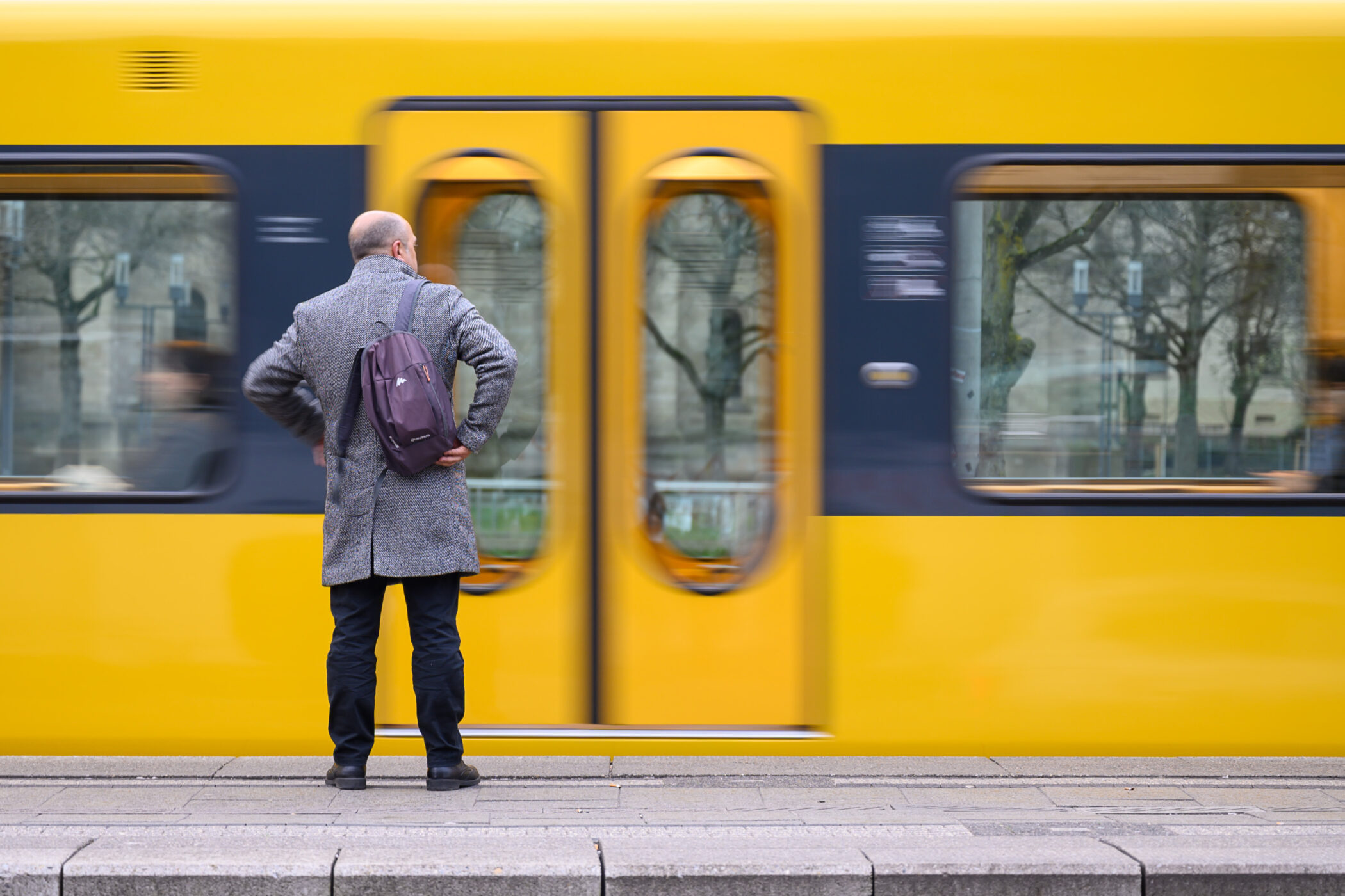 Mann im Mantel vor gelber Bahn