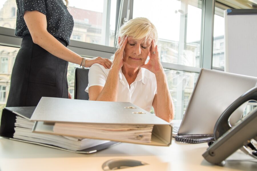 Eine Frau sitzt in einem Büro, während ihre Kollegin sie tröstet