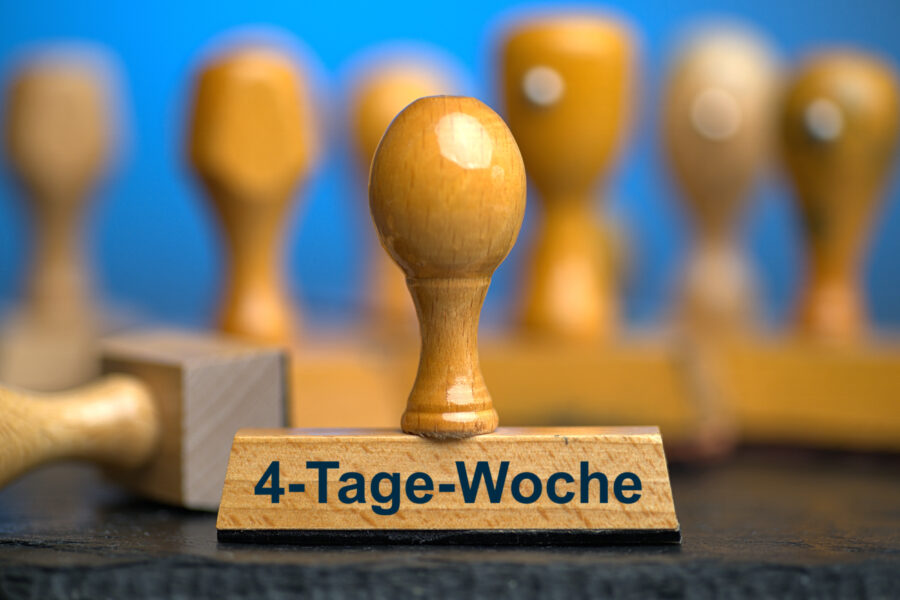 Ein Holzstempel mit der Aufschrift "4-Tage-Woche" auf einer Schieferplatte