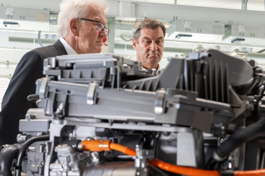Winfried Kretschmann und Markus Söder stehen im Zentrum für Sonnenenergie- und Wasserstoff-Forschung hinter einem Brennzellenmotor.