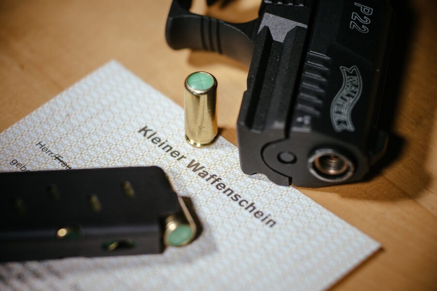 Ein Kleiner Waffenschein liegt zwischen einer Schreckschuss-Pistole "Walther P22", einem Magazin und einer Knallpatrone.