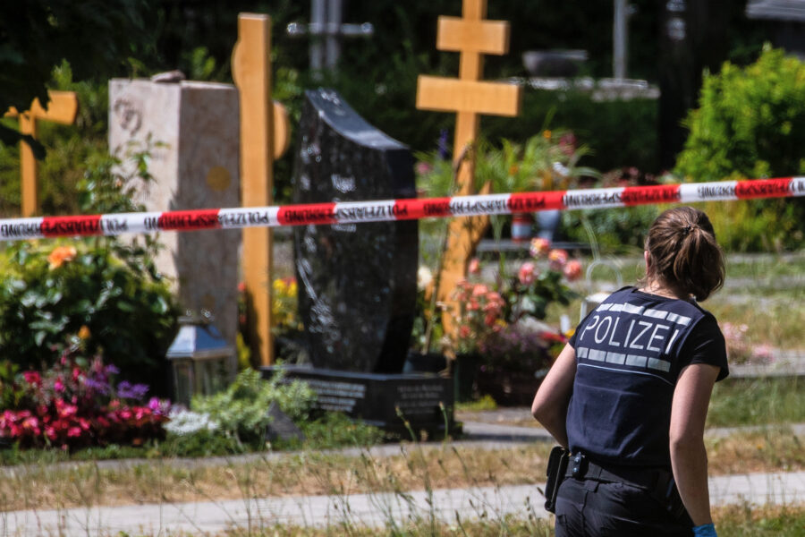 Eine Polizistin geht über den abgesperrten Teil an einem Tatort auf einem Friedhof. Durch den Wurf eines explodierenden Gegenstands auf eine Trauergemeinde gab es mehrere Verletzte.