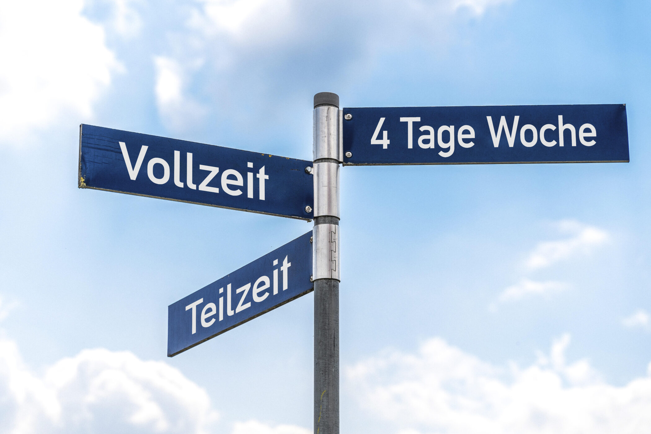 Verkehrsschild mit Wegweiser - Vollzeit, Teilzeit und 4 Tage Woche vor blauem Himmel