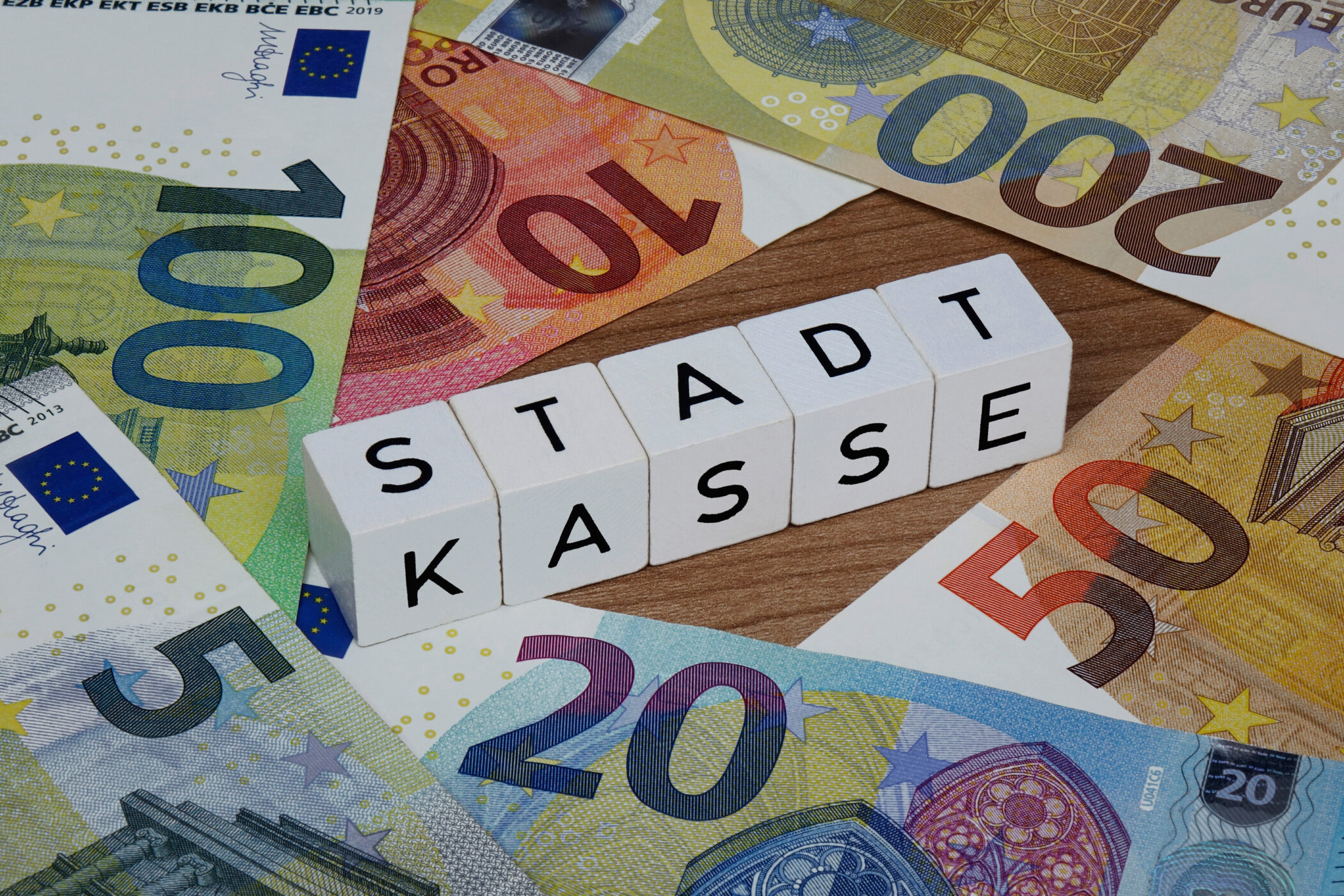 Euro-Geldscheine umgeben Würfel mit dem Text "STADTKASSE".