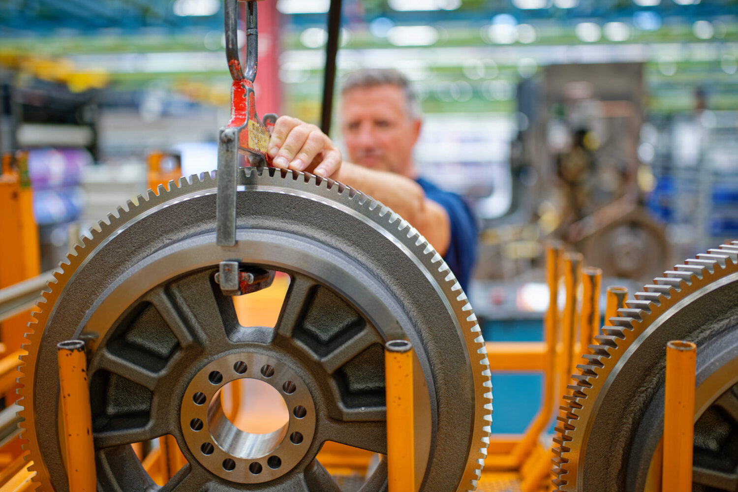Person bedient Hebevorrichtung mit großem Zahnrad in Fabrikumgebung.