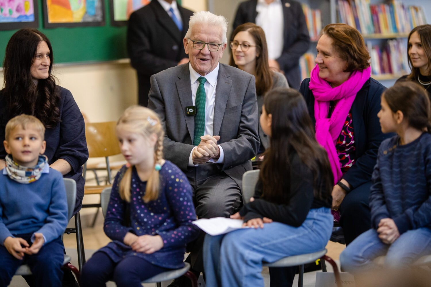 Mehrere Erwachsene und Kinder sitzen in einem Klassenzimmer.