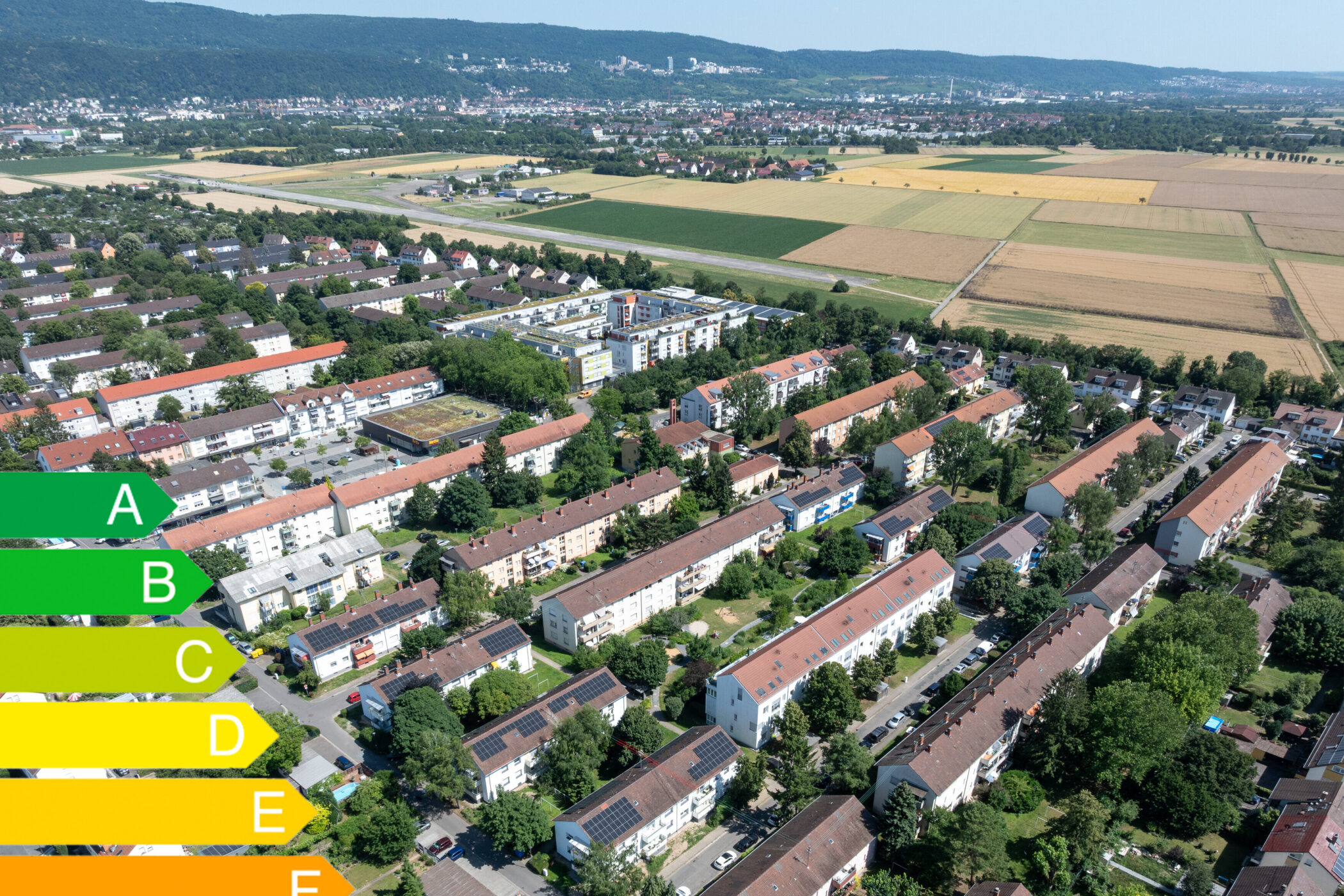 Luftaufnahme einer Wohnsiedlung mit Energieeffizienzskala von A bis G links.