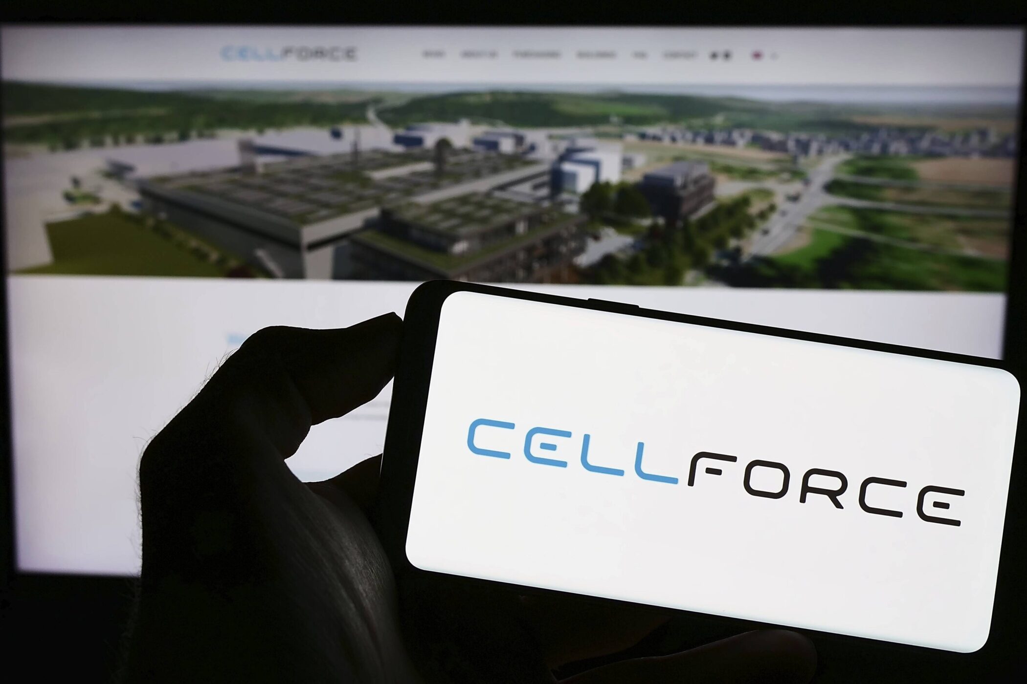 Hand hält Smartphone mit "CELLFORCE"-Logo vor unscharfem Bildschirmhintergrund mit Gebäudeansicht.