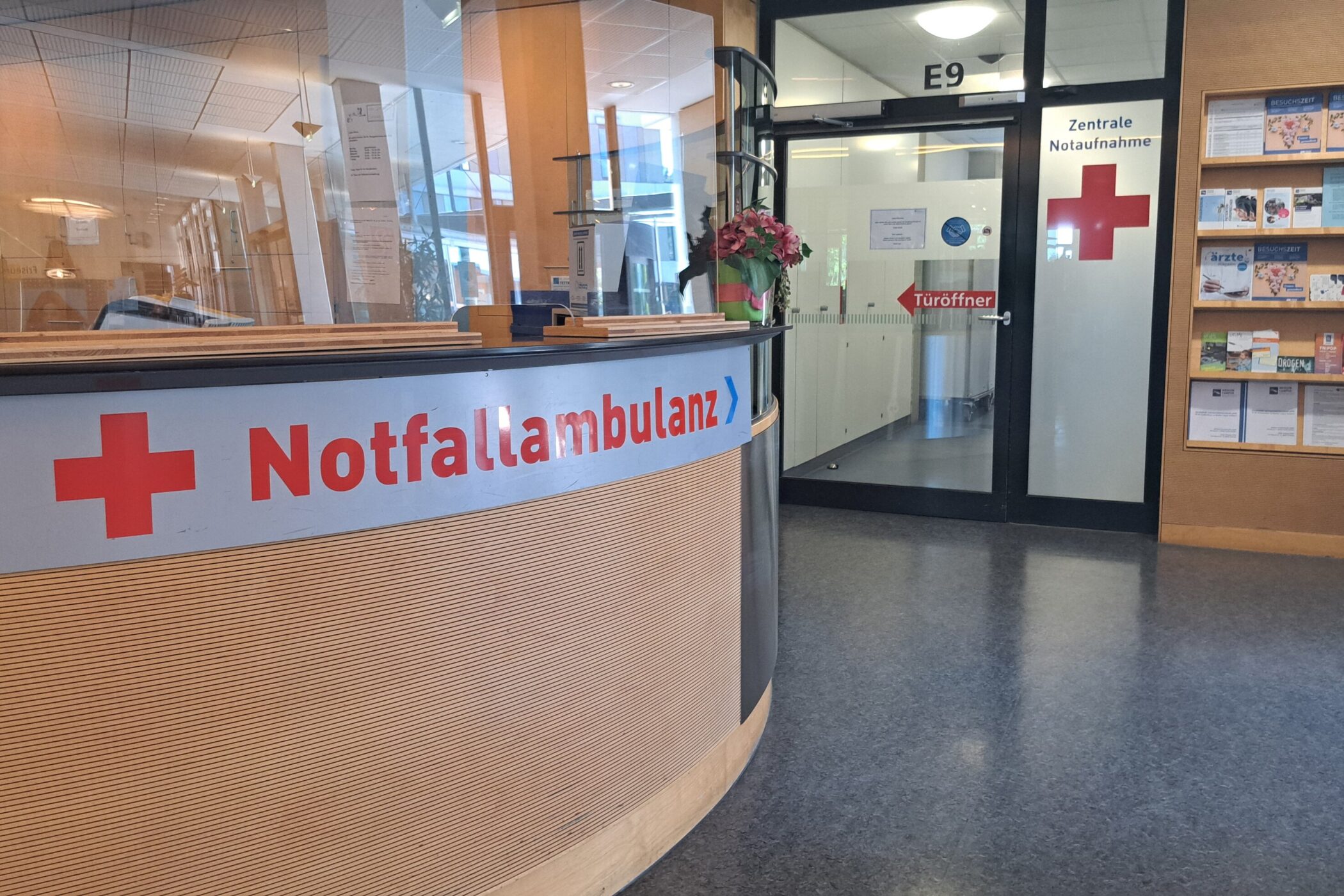 Empfangsbereich der Notfallambulanz mit Schildern und Broschüren an der Wand.
