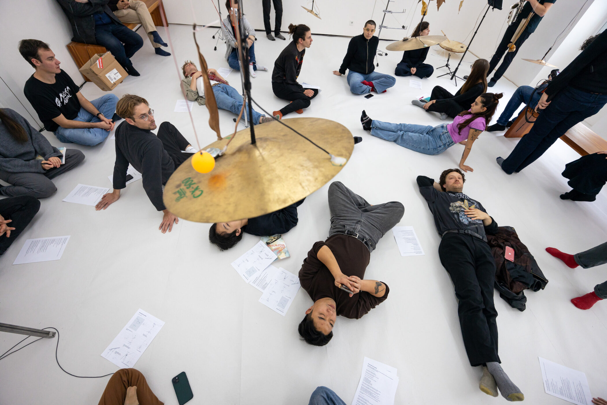 Mehrere Personen sitzen und liegen auf dem Boden, umgeben von Notenblättern.