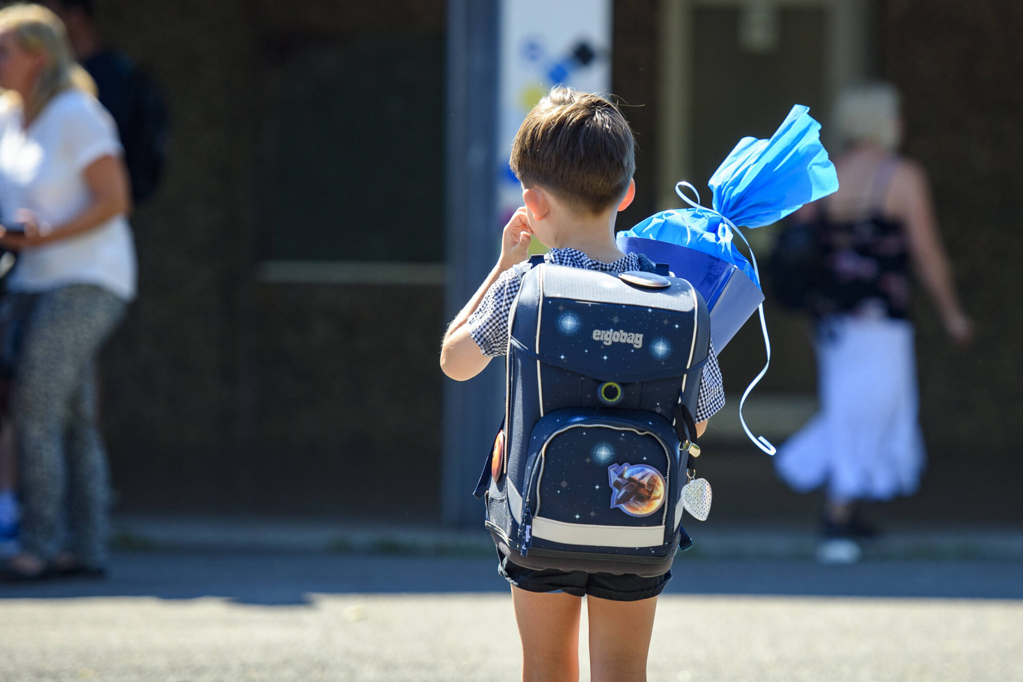 Kind mit Rucksack und Schultüte von hinten, im Freien.