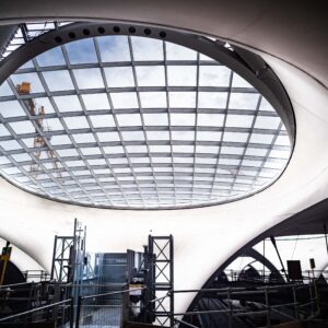 Große, ovale Glasdecke mit sichtbarem Baukran darüber. Darunter Baustelle.