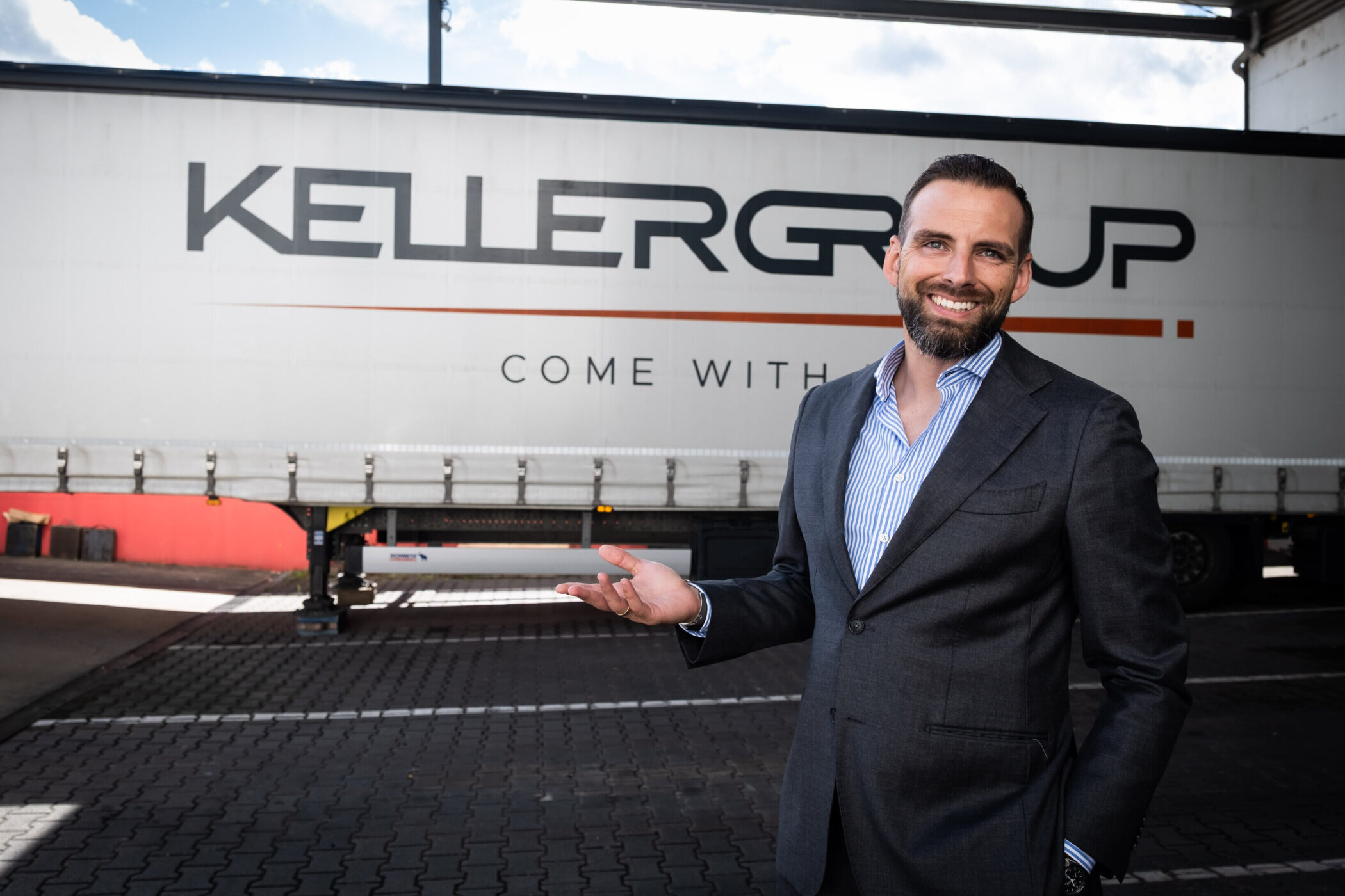 Mann im Anzug vor LKW mit Aufschrift "KELLERGROUP COME WITH".