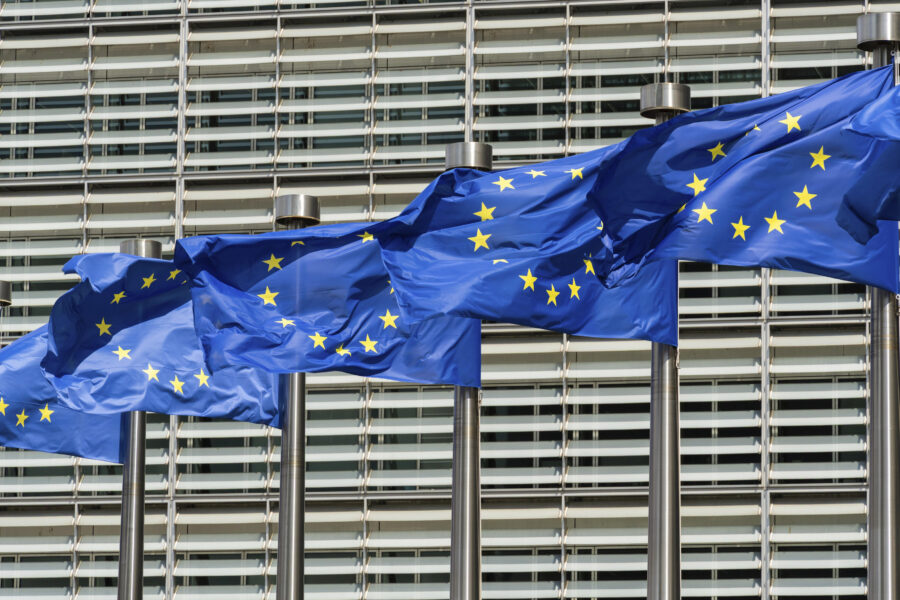 Vier EU-Flaggen wehen vor einem modernen Gebäude.