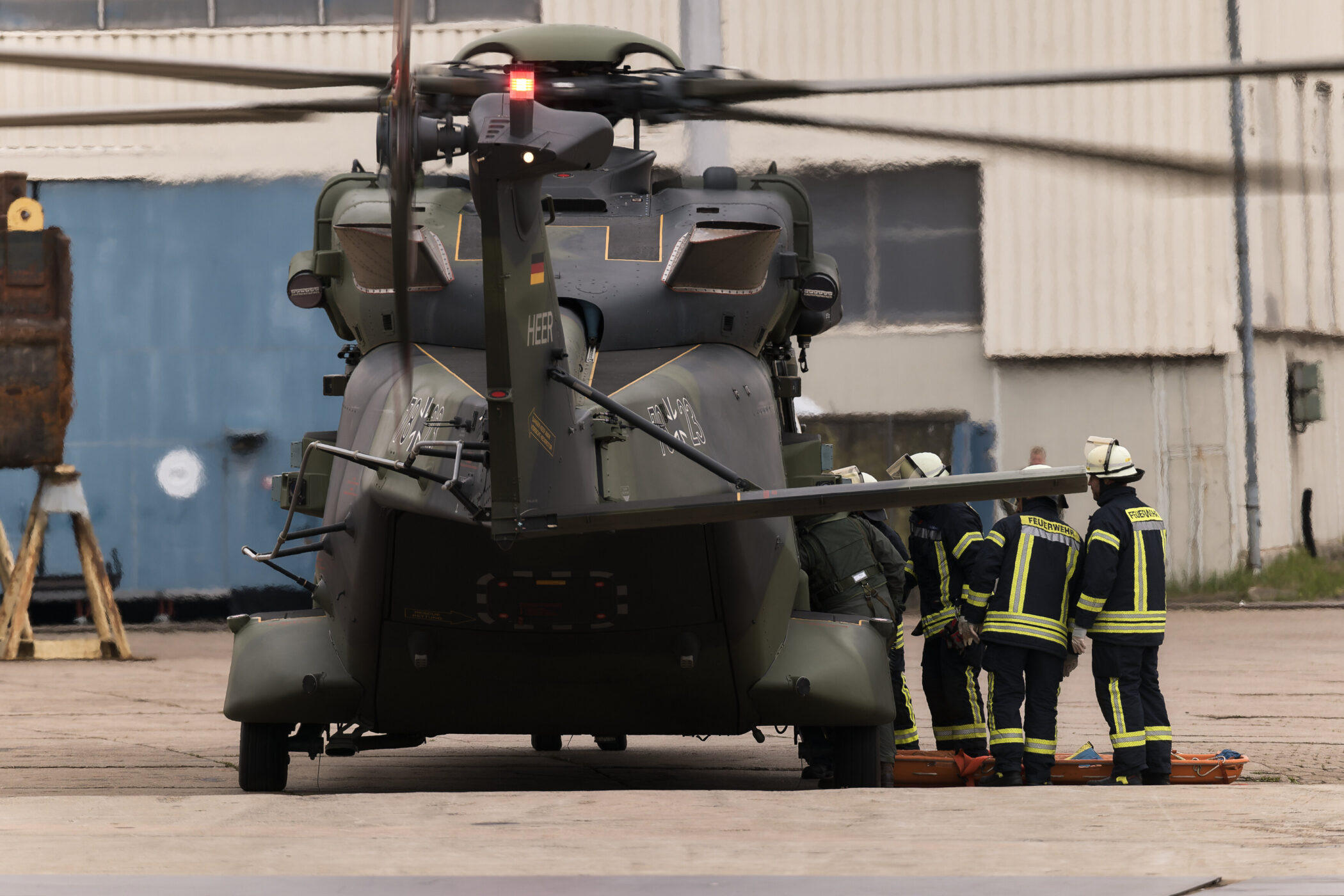 Hubschrauber mit Feuerwehrleuten in Schutzkleidung auf einem Flugfeld.