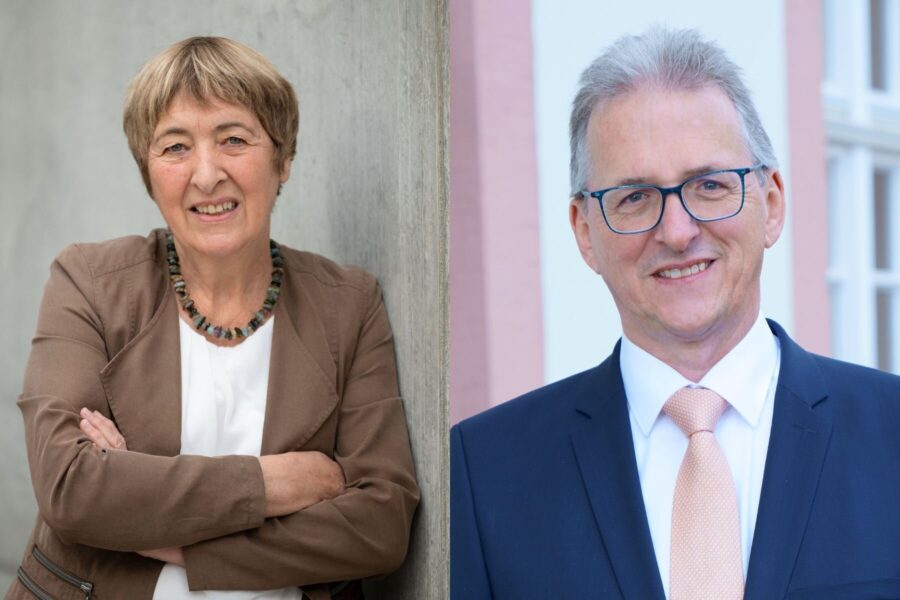 Zwei Personen, eine Frau links, ein Mann rechts, beide lächelnd.