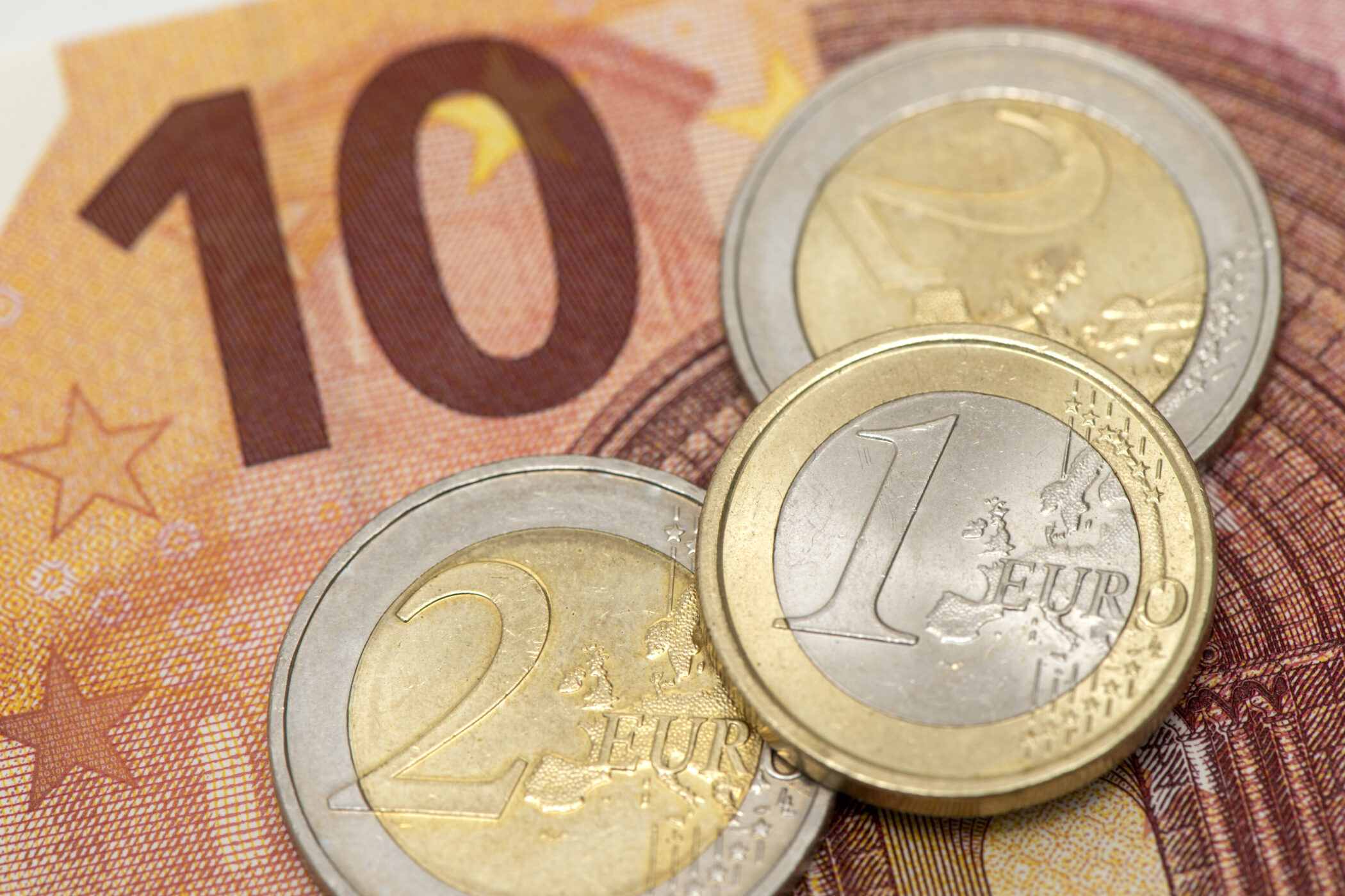 Zwei 2-Euro-Münzen, eine 1-Euro-Münze auf einem 10-Euro-Schein.