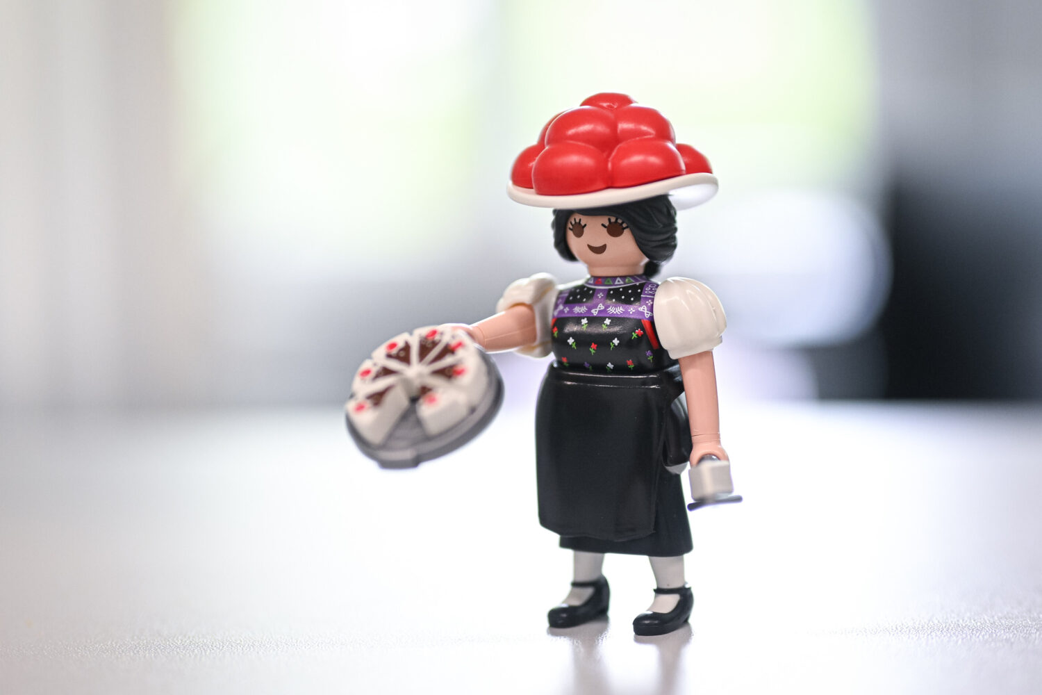 Spielzeugfigur mit rotem Hut und Kuchen in der Hand.