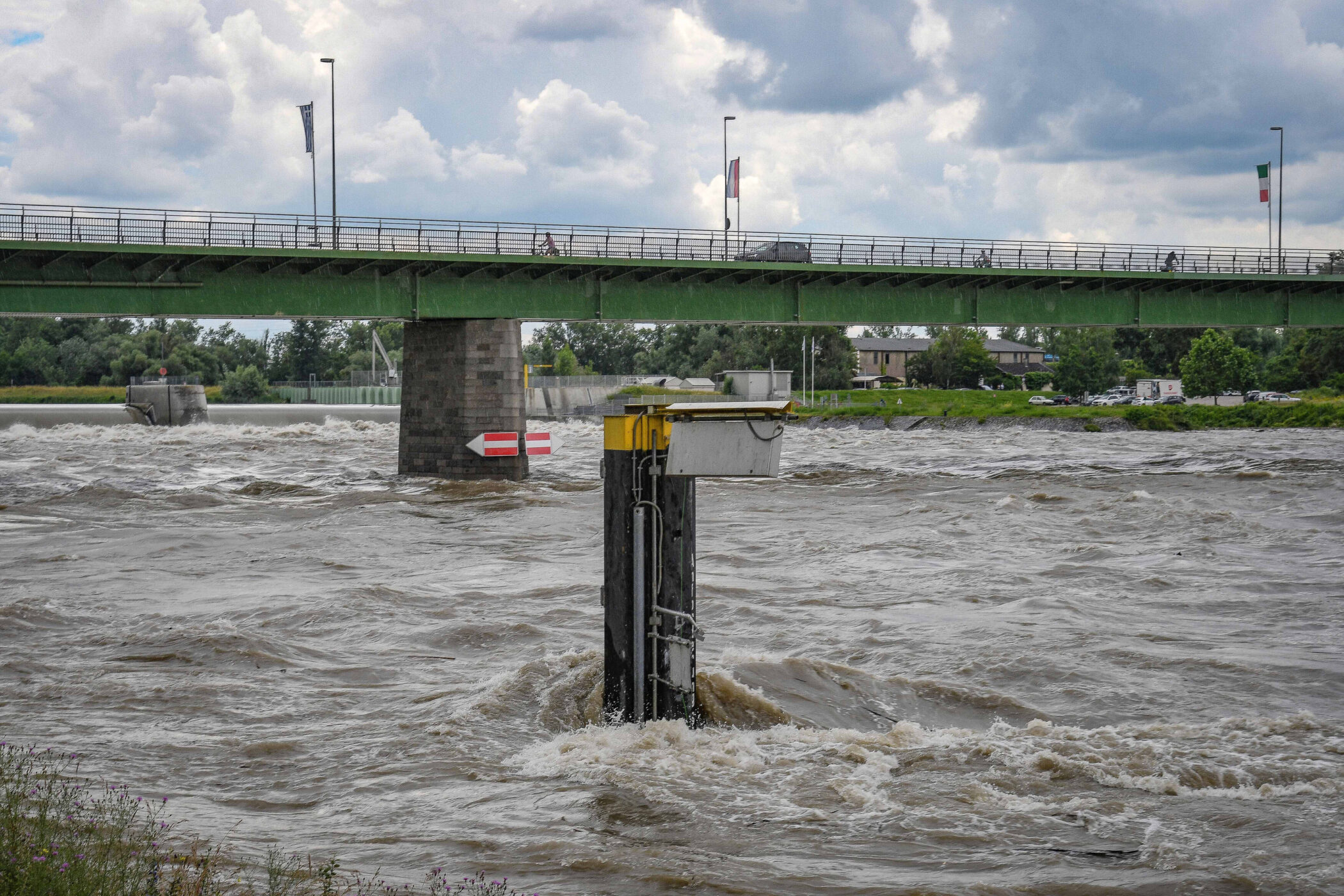 Brücke über einen stark fließenden Fluss, Pfeiler mit Schildern im Wasser.