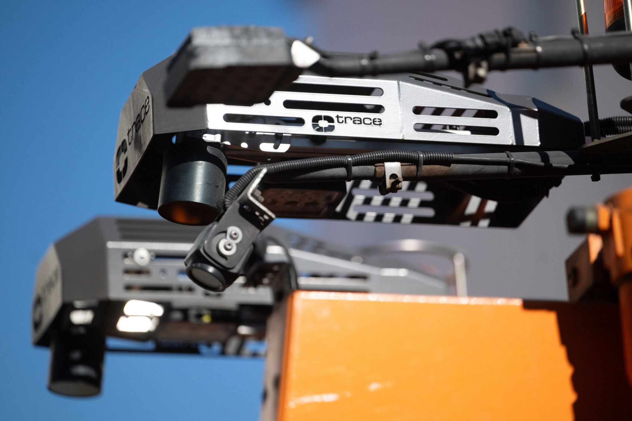 Zwei graue Geräte mit Kabeln und Sensoren, blauer Himmel im Hintergrund.