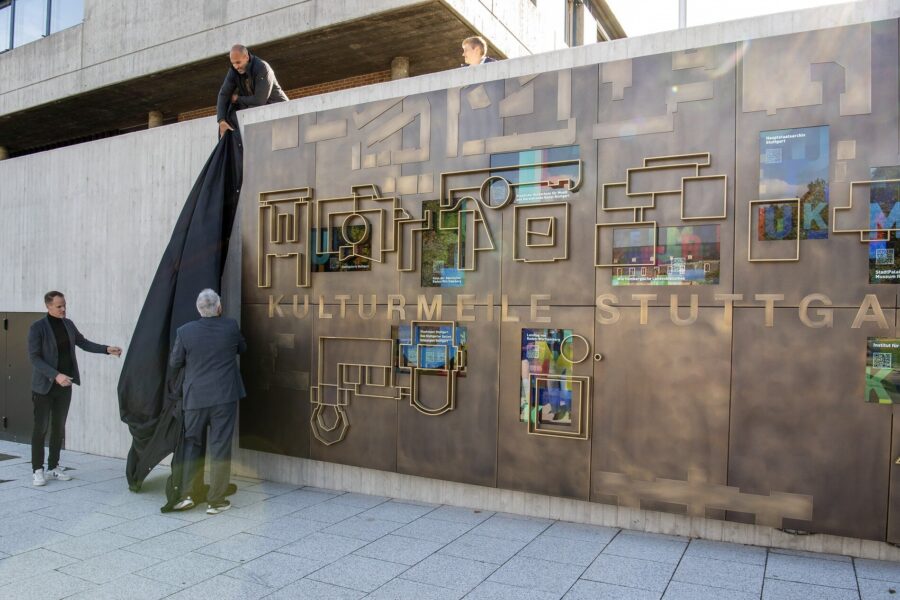 Drei Männer enthüllen eine Wand mit der Aufschrift "KULTURMEILE STUTTGART".