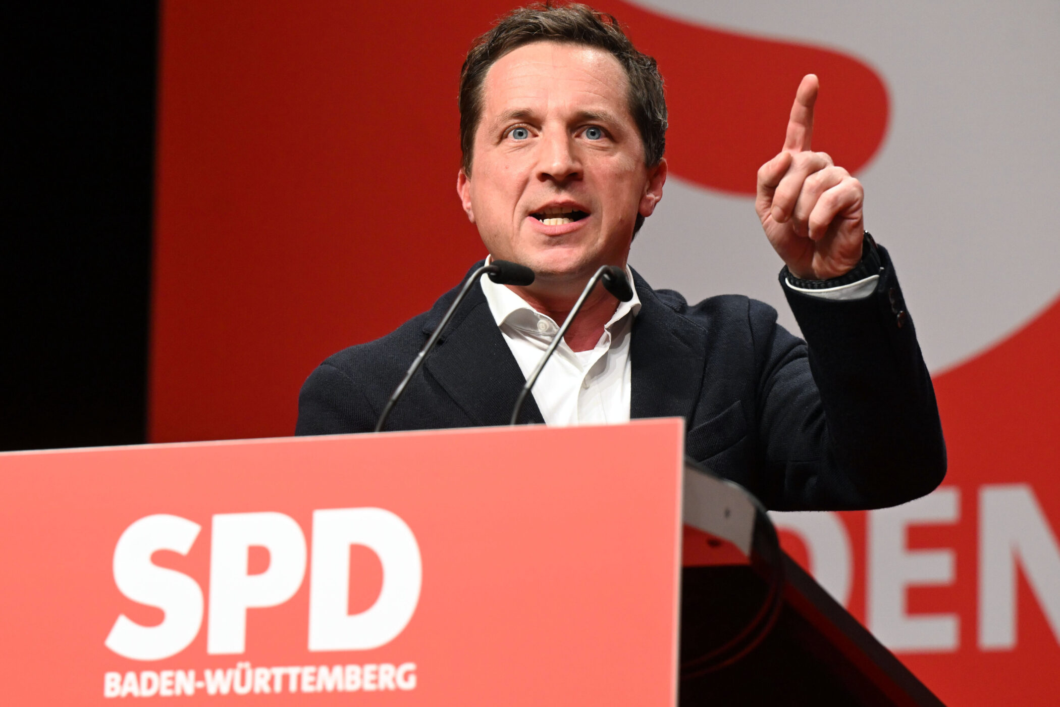 Mann spricht am Rednerpult mit SPD-Logo, hebt den Zeigefinger.