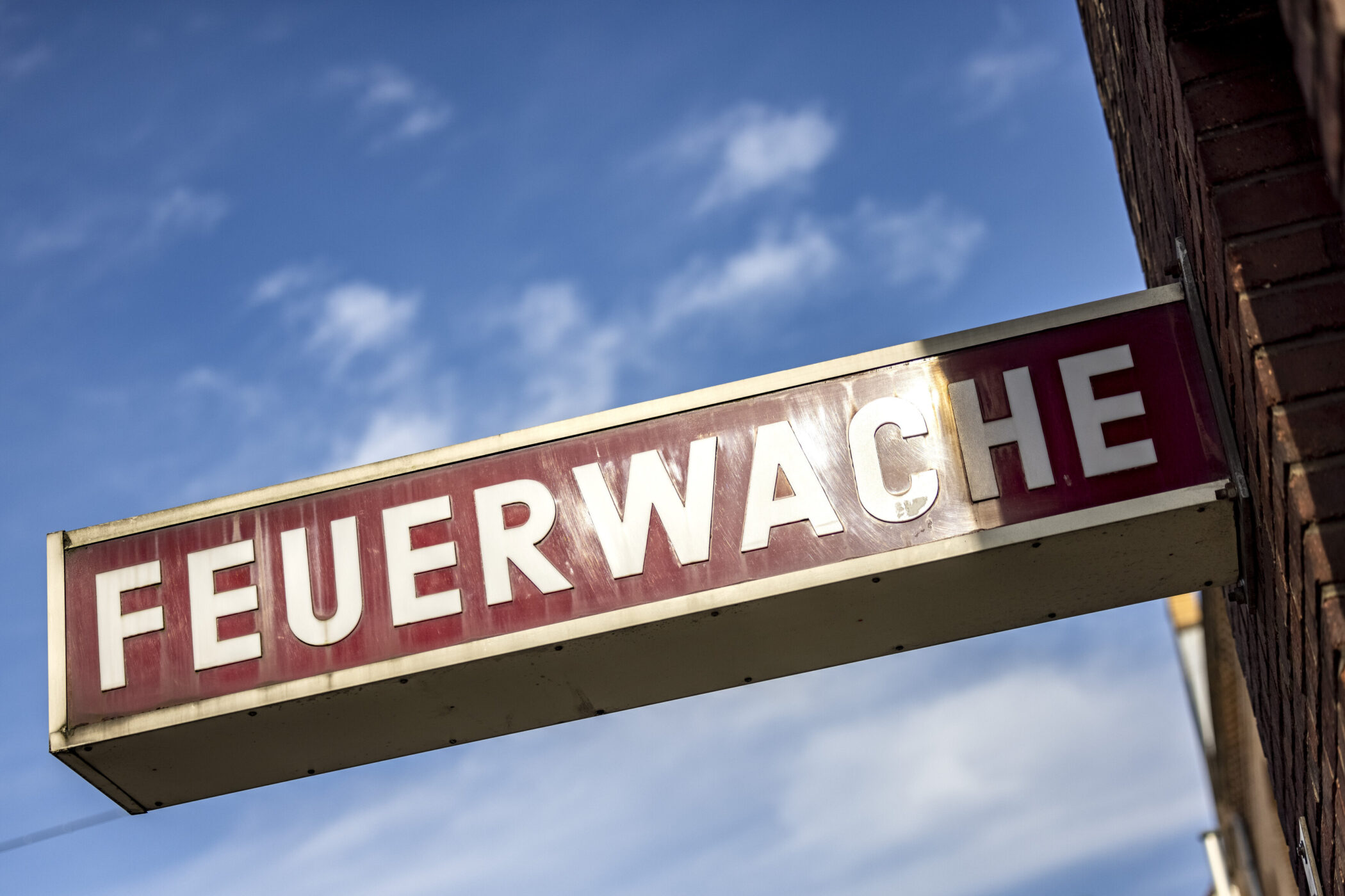 Schild mit der Aufschrift "FEUERWACHE" vor blauem Himmel.