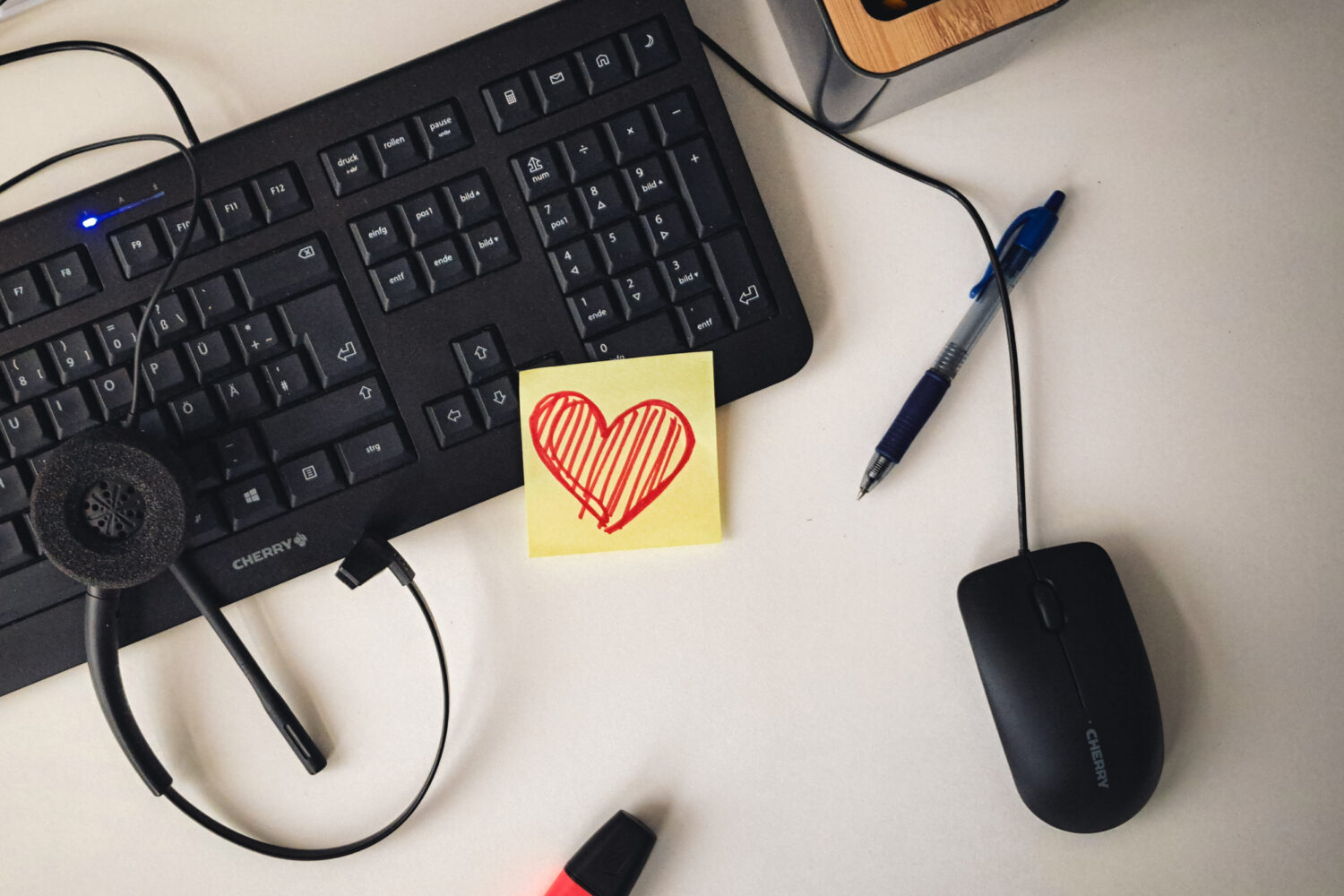 Tastatur, Maus, Headset, Stift, Textmarker, Notiz mit Herz auf Schreibtisch.
