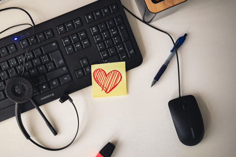 Tastatur, Maus, Headset, Stift, Textmarker, Notiz mit Herz auf Schreibtisch.