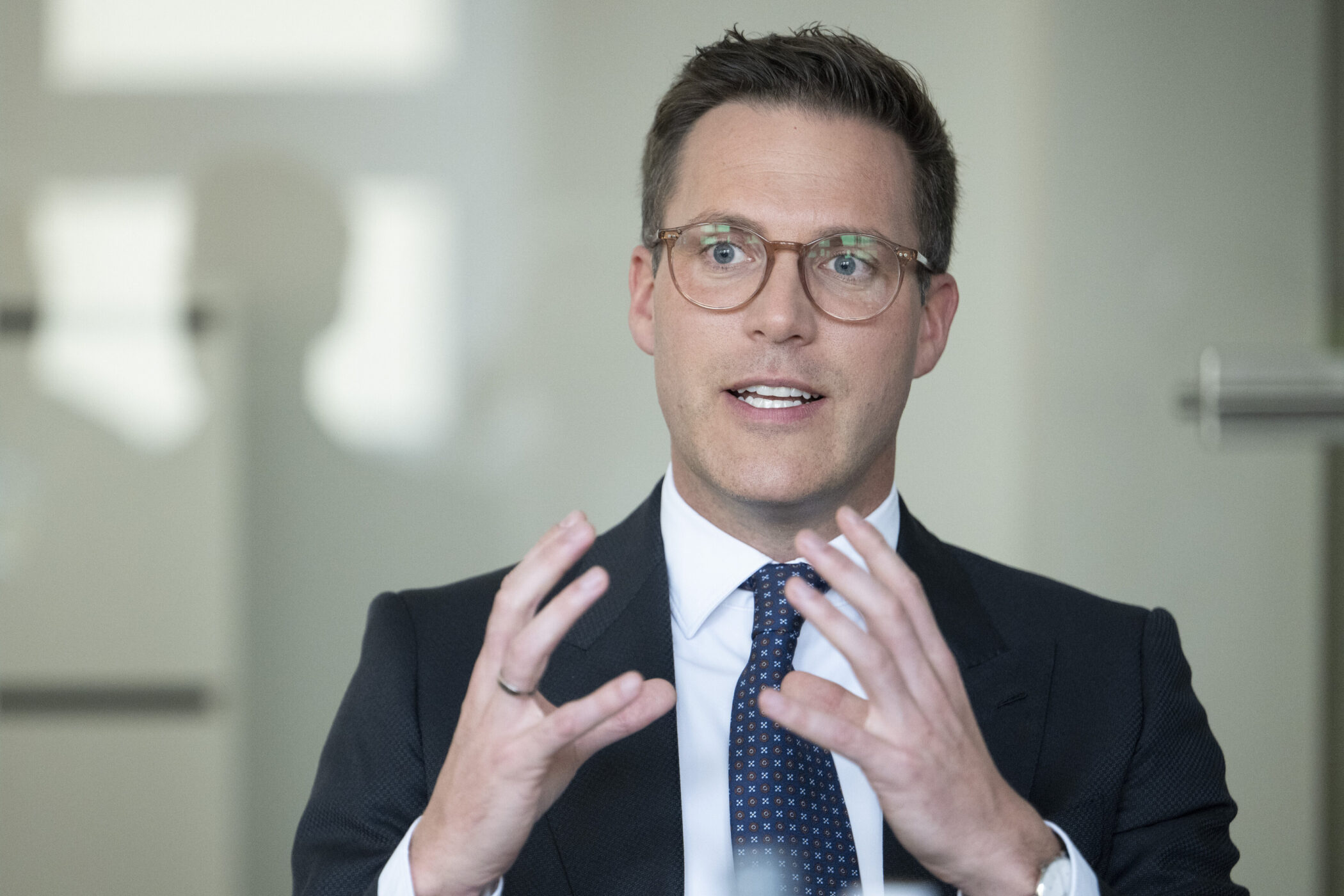 Mann mit Brille und Anzug spricht gestikulierend.