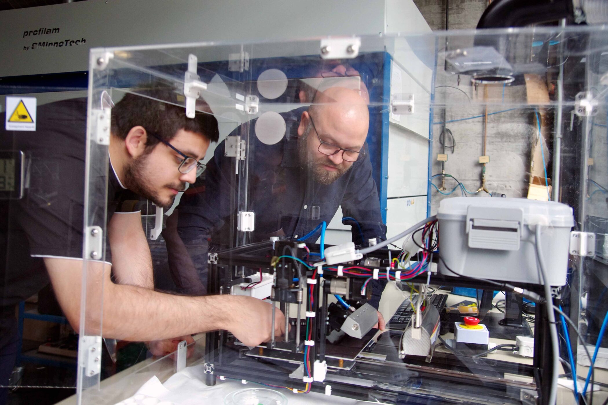 Zwei Männer arbeiten an einem Gerät in einem Labor.