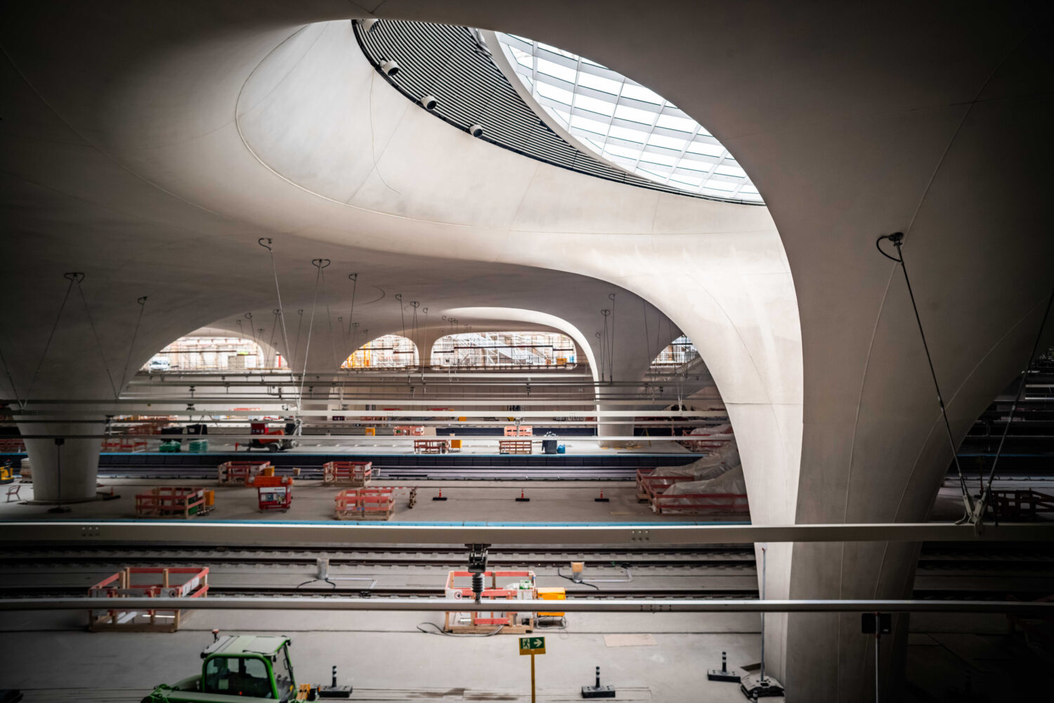 Große, moderne Bahnhofshalle mit geschwungenen Decken und Baustellenabsperrungen.