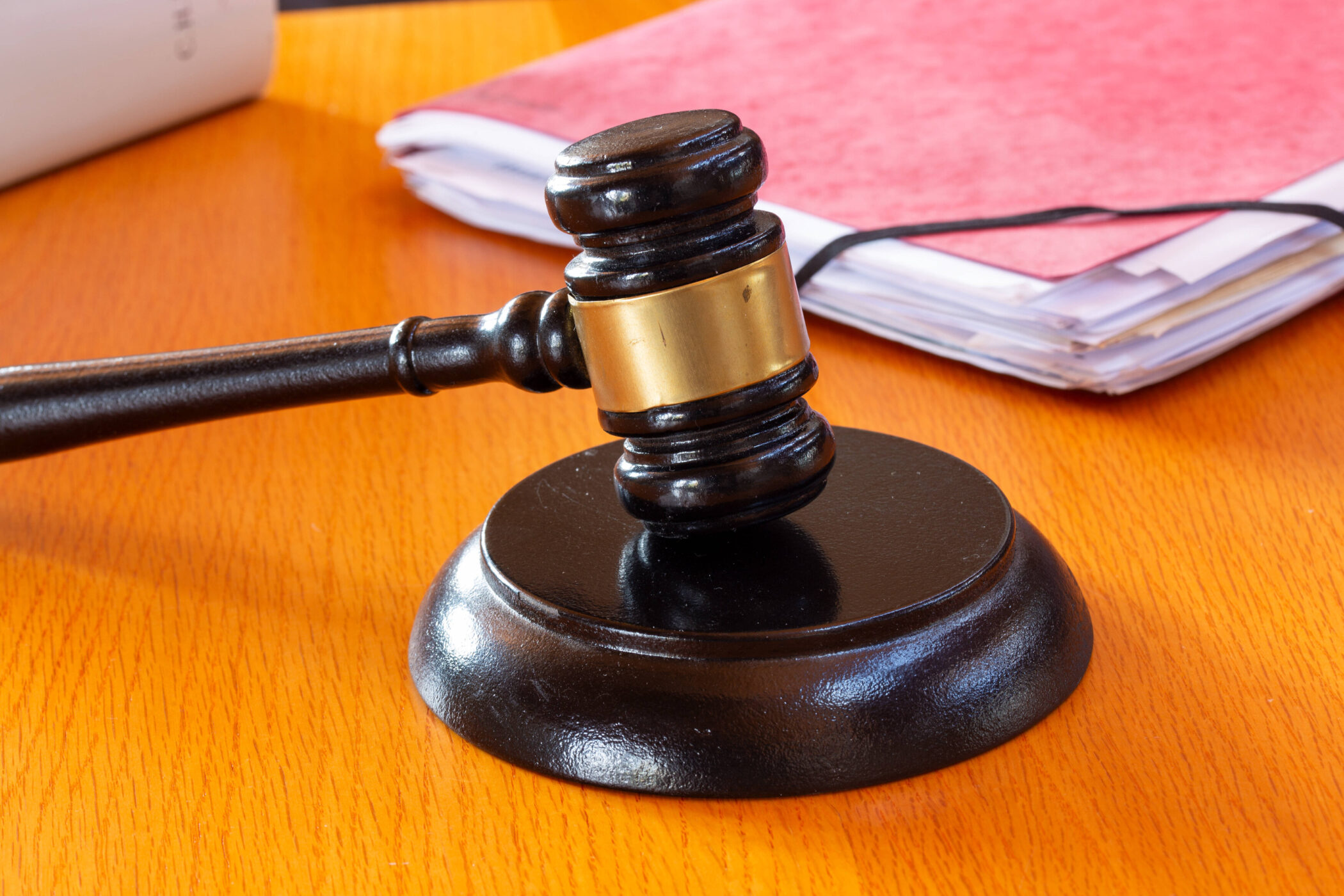 Richterhammer auf Holztisch, daneben Papierstapel.