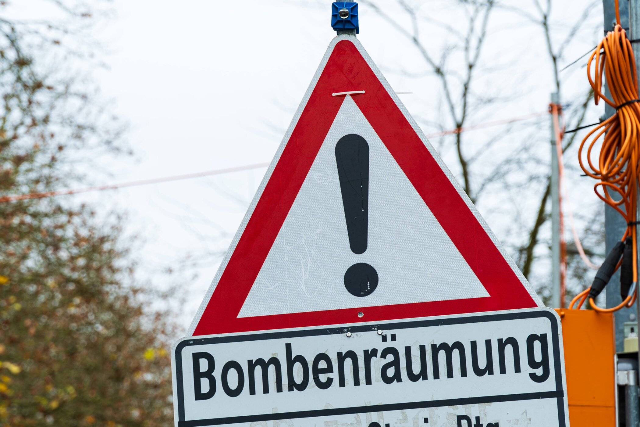 Dreieckiges Warnschild mit Ausrufezeichen, darunter "Bombenräumung".