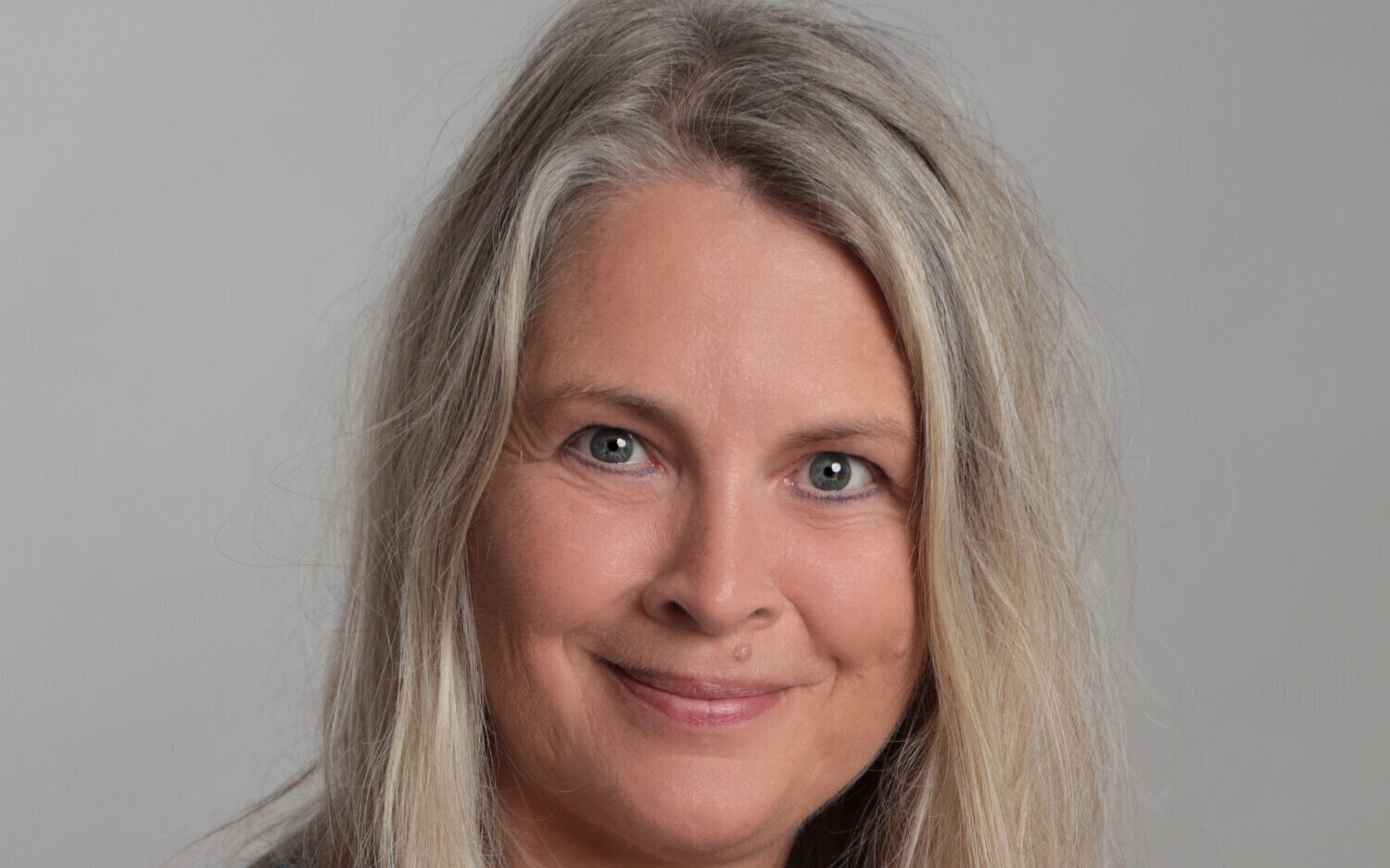 Eine Frau mit langen blonden Haaren lächelt in die Kamera.