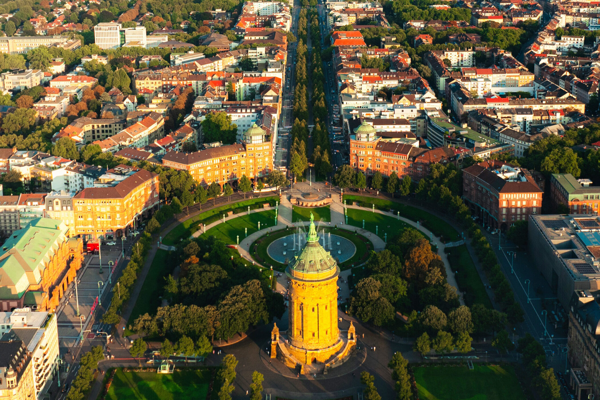 Luftaufnahme eines runden Turms mit Park und umliegenden Gebäuden in einer Stadt.