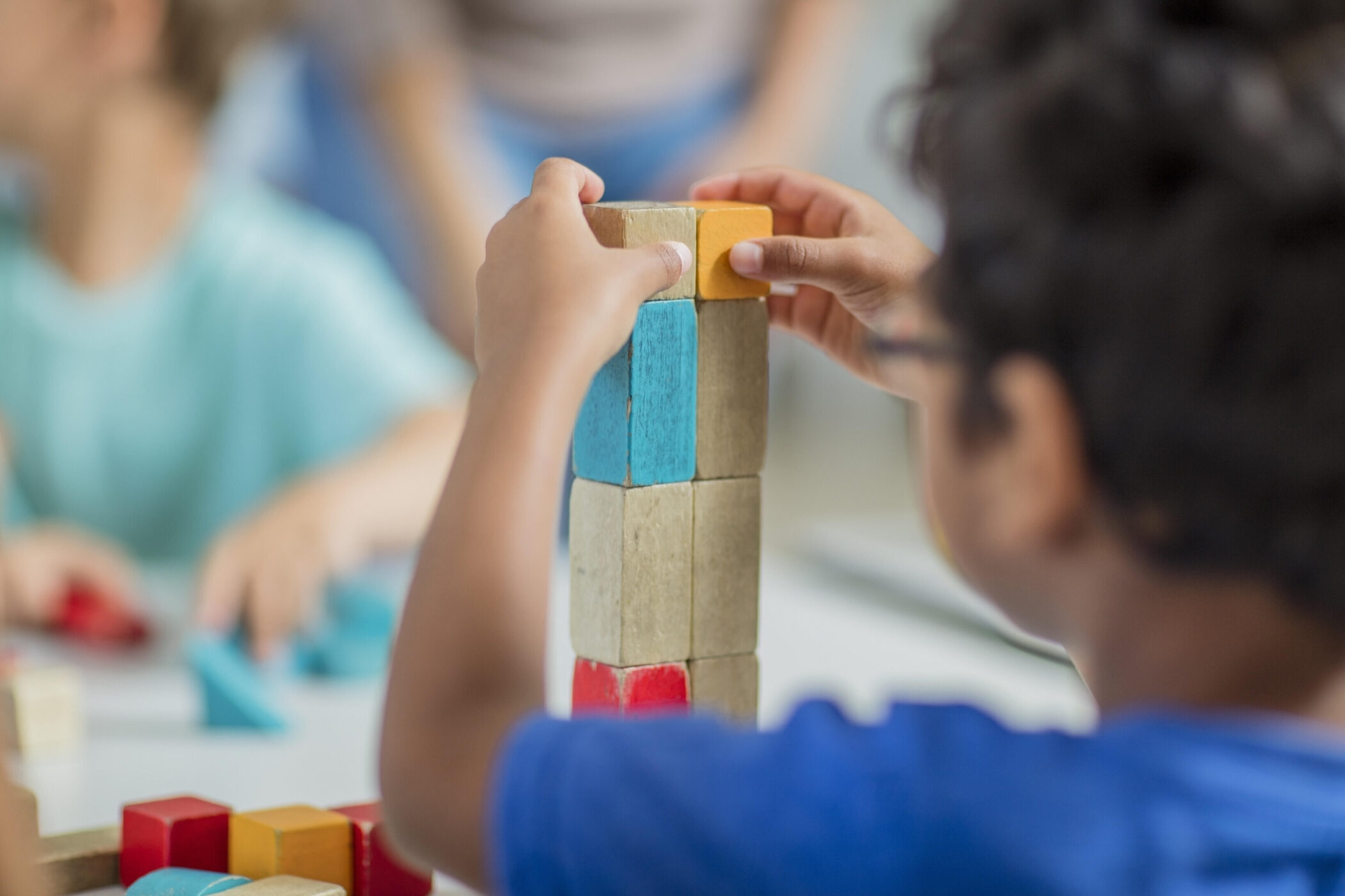Kind stapelt bunte Holzklötze auf einem Tisch.