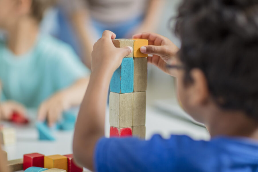 Kind stapelt bunte Holzklötze auf einem Tisch.