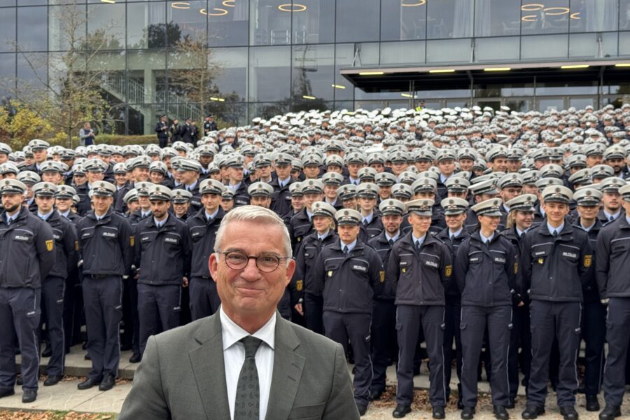 Eine große Gruppe uniformierter Personen vor einem Gebäude, ein Mann im Anzug vorne.
