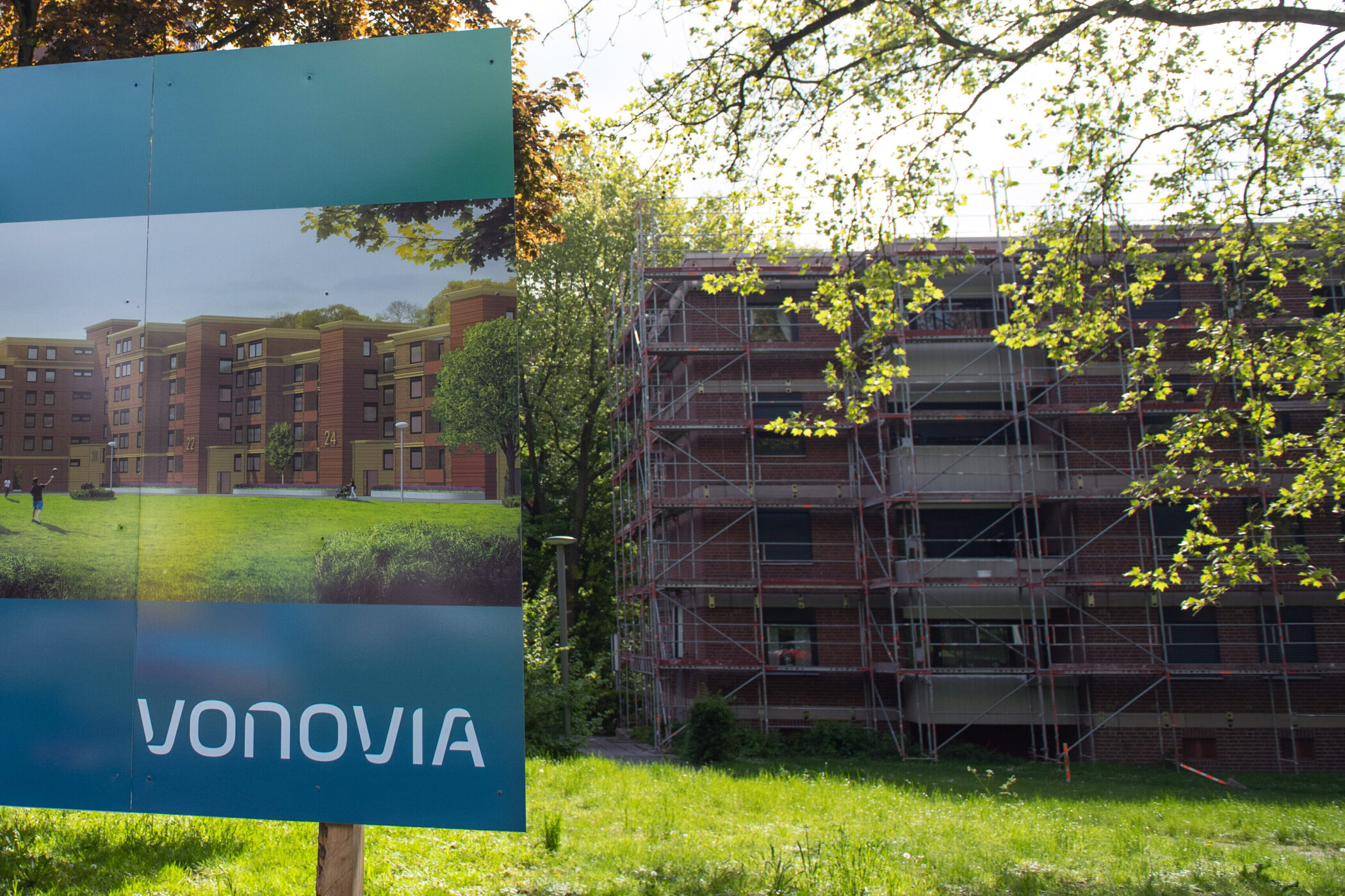 Bauschild mit "Vonovia" vor einem eingerüsteten Gebäude, Bäume im Hintergrund.