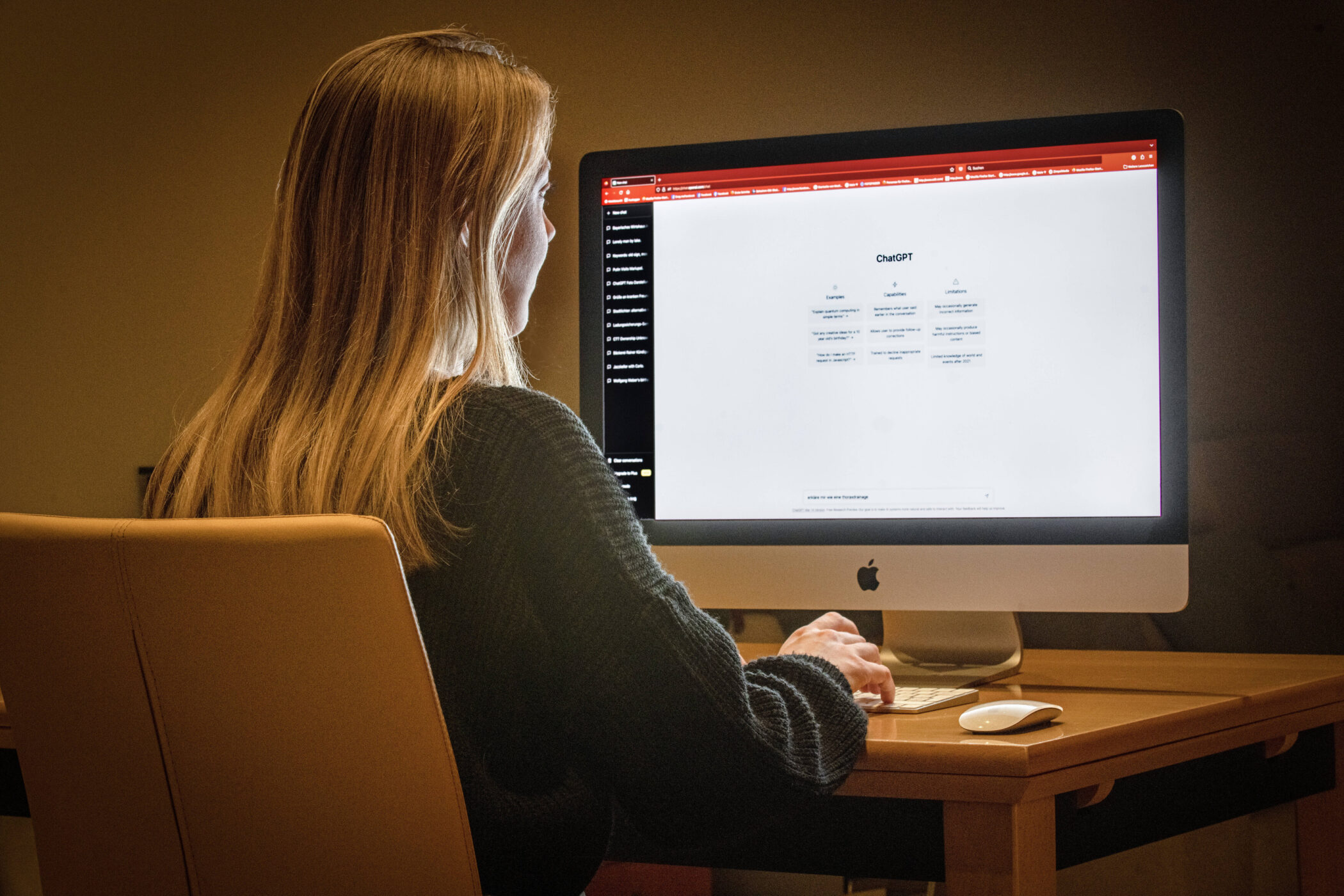 Person am Schreibtisch arbeitet an einem iMac-Computer.