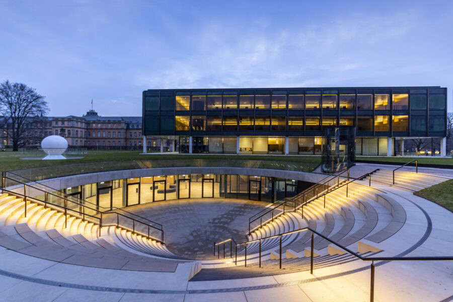 Modernes Gebäude mit beleuchteten Stufen und Glasfassade bei Dämmerung.