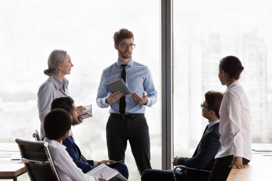 Sechs Personen in einem Besprechungsraum, eine Person spricht.