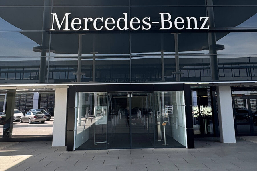 Eingang eines Gebäudes mit Mercedes-Benz-Schriftzug darüber.