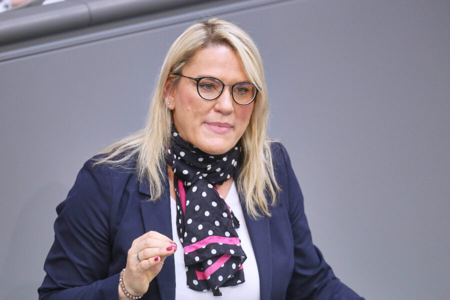 Eine Frau mit Brille und Schal spricht gestikulierend.